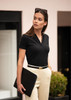 A black V-neck polo shirt worn by a woman, paired with light-coloured trousers and holding a black laptop bag.