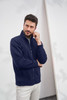 A men's navy jacket with a zip, featuring a high collar and pockets, worn by a model.