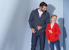 A grey hooded jacket on a man and a red hooded jacket on a boy, both smiling against a light blue background.