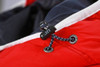 A close-up of a red vest featuring a black toggle and blue decorative cord detail.