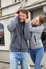 A grey ladies hooded jacket displayed on a woman, featuring a zip, pockets, and a logo.