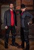 Workwear pants in black with reflective detailing, modelled by a man and a woman in red shirts and jackets.