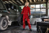Red workwear pants are worn by a person in a workshop setting, alongside a vehicle and tyres.