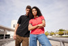 A black and a pink ladies polo shirt worn by a man and a woman outdoors, featuring a logo.
