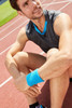 A close-up of a man wearing a blue Terry Wristband on a running track, seated and smiling. He’s in athletic wear.