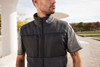 A men's fleece vest in grey with a black panel, featuring a zip front and a high collar.