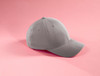 A grey cap with a curved brim and a branding logo, displayed against a pink background.