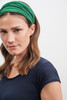 A woman wearing a green bandanna headband, styled with loose waves, against a neutral background.