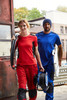 A red work T-shirt and blue work T-shirt being worn by a man and woman, both in casual work attire.