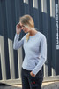 A grey long-sleeve t-shirt displayed on a model against a striped background, featuring a logo.