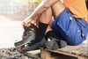 Worker socks in black and grey worn with work boots, paired with shorts, on a wooden pallet outdoors.