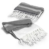 A grey and white Ohau Throw Blanket with tasselled edges, featuring a geometric pattern. It has a branding logo.
