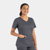 A grey women's double V-neck top with short sleeves and a pocket. The model is smiling and standing confidently.