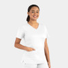 A woman in a white double v-neck top with short sleeves and a pocket, smiling against a light background.