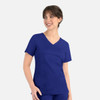 A woman is wearing a navy blue curved mock wrap top with short sleeves and pockets. The top features a V-neck design.