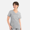 A woman in a light grey curved mock wrap top with short sleeves, featuring two front pockets.