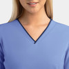 A women's light blue v-neck top featuring a navy contrast trim, with an embroidered logo on the side.