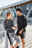A pair of models wearing a grey long-sleeved ladies sports shirt and matching activewear. The shirt features colour detailing.