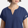 A navy women's top featuring a V-neckline, short sleeves, and a small front pocket. It has a logo on the sleeve.