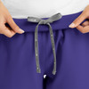 A close-up of a purple jogger's waistband with a grey tie, featuring a logo on the tie.