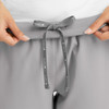 A close-up of grey women's joggers featuring a drawstring waist, held by hands, showcasing a smooth fabric texture.