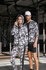 A ladies' soft shell jacket featuring a black and white graphic pattern, accompanied by a male model in matching attire.