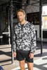 A men's sports jacket in a black and white abstract pattern, featuring a zip front and a hood, suitable for athletic wear.