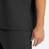 A close-up of a men's tuckable v-neck top in black, featuring a side slit and part of a hand. There is a logo visible.