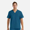 A men's tuckable v-neck top in teal blue with a chest pocket and a logo on the sleeve.