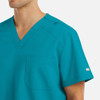 A bright teal men's tuckable v-neck top with a pocket and branding detail on the arm.