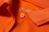 An orange ladies active polo shirt featuring a collar and a button, with a branding label inside.