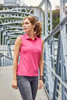 A sleeveless pink polo shirt on a model standing on a bridge, featuring a collar and a logo.