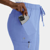 A pair of light blue women's cargo pants with a full elastic waistband, featuring side pockets and a phone being placed in one.