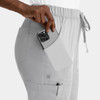A pair of light grey cargo pants with an elastic waistband, featuring side pockets and a phone being placed in one pocket.