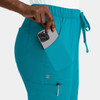 A pair of turquoise women's cargo pants featuring a full elastic waistband and side pockets, with a phone partially visible.