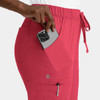 A pink cargo pant with a full elastic waistband, featuring a hand placing a phone into the side pocket.