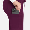 A woman inserting a smartphone into the pocket of purple cargo pants. The pants have a drawstring waist and a logo.