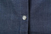 A close-up of a ladies denim blouse showing a button and fabric texture in dark blue denim.