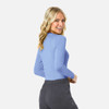 A woman in a light blue long-sleeve underscrub tee faces away, showcasing a relaxed fit and subtle branding.