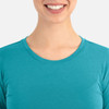 A close-up of a smiling woman wearing a teal underscrub tee, featuring a round neckline.