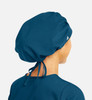 A unisex bouffant scrub cap in dark teal, styled with a gathered design and adjustable ties at the back.