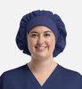 A unisex bouffant scrub cap in navy blue, featuring a logo, worn by a smiling person in a matching scrub top.