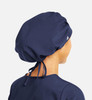 A unisex bouffant scrub cap in navy blue, featuring a tie closure and a logo on the side.