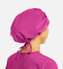 A unisex bouffant cap in a vibrant pink colour, featuring a drawstring tie at the back and a logo.