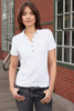 A white Ladies Pima Polo shirt featuring a button placket, displayed on a woman in a contemporary setting.