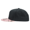 A structured camo snapback cap in black with a pink camo brim and a logo on the side.