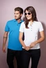 A blue men's Pima polo shirt and a white women's polo shirt are displayed on a light purple background.