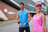 A blue active tank top on a man and a pink active tank top on a woman, both posing outdoors.