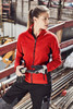 A red polar fleece jacket with a zip, worn by a woman, featuring a logo, set in a construction environment.