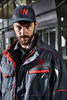 A workwear jacket in navy with red accents worn by a man. The jacket features pockets and has a logo.